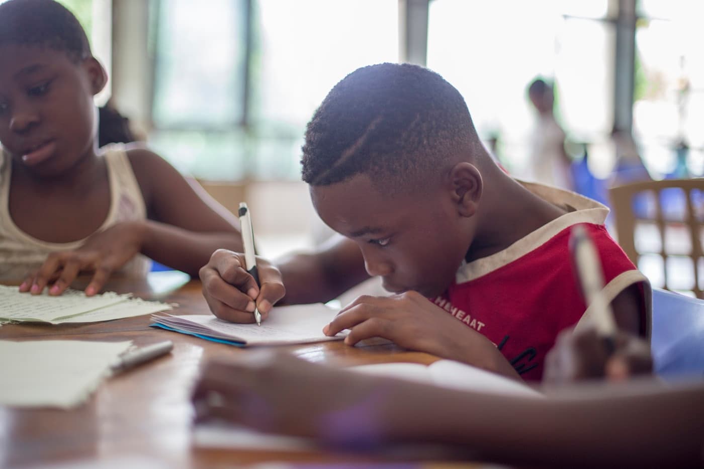 Des enfants concentrés font leurs devoirs autour d'une table