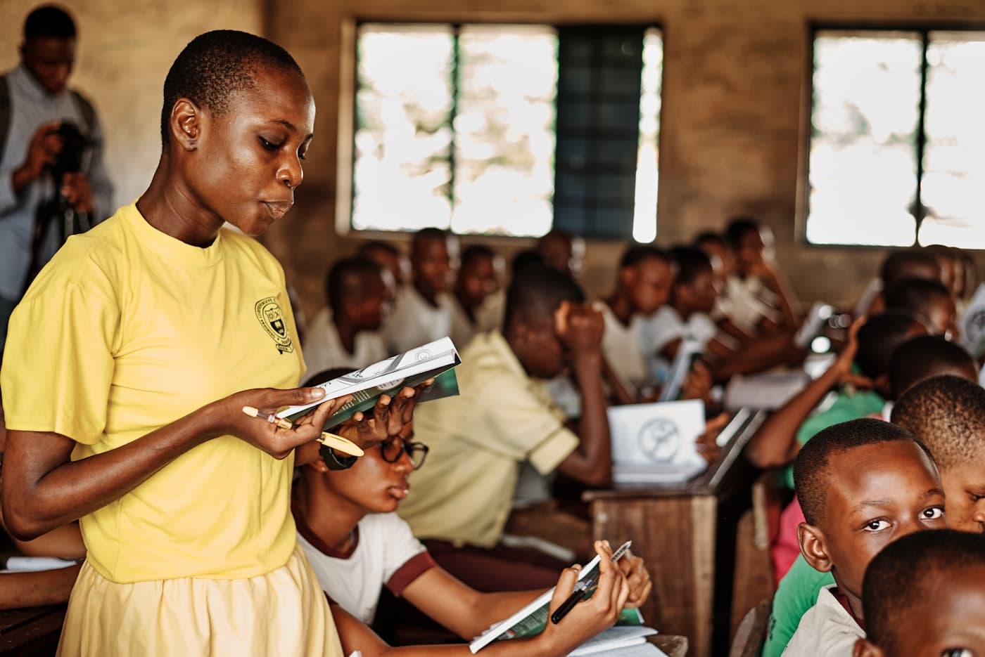 Une enseignante fait cours devant sa classe, un livre à la main